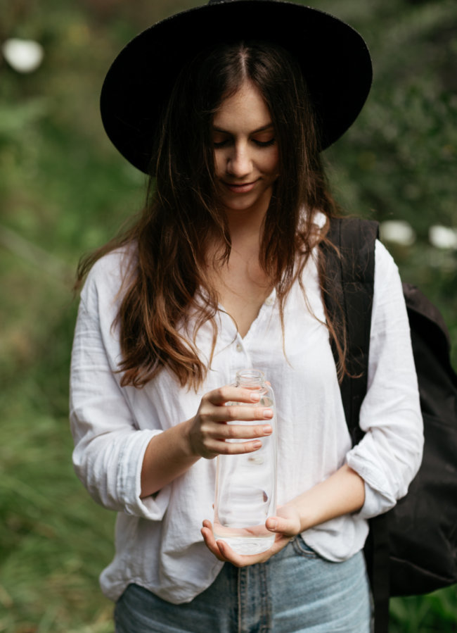 Our water 2 Woman outdoors holding a glass bottle of clear water