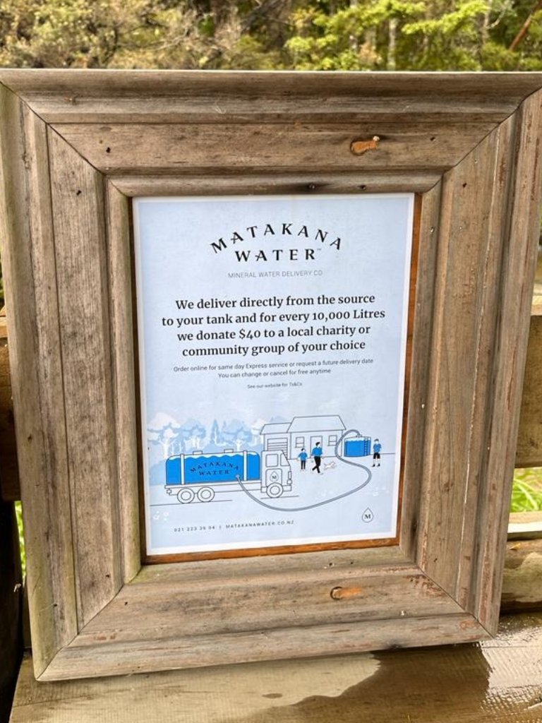 Framed sign describing Matakana Water's delivery service and $40-per-10,000-litre charity donation