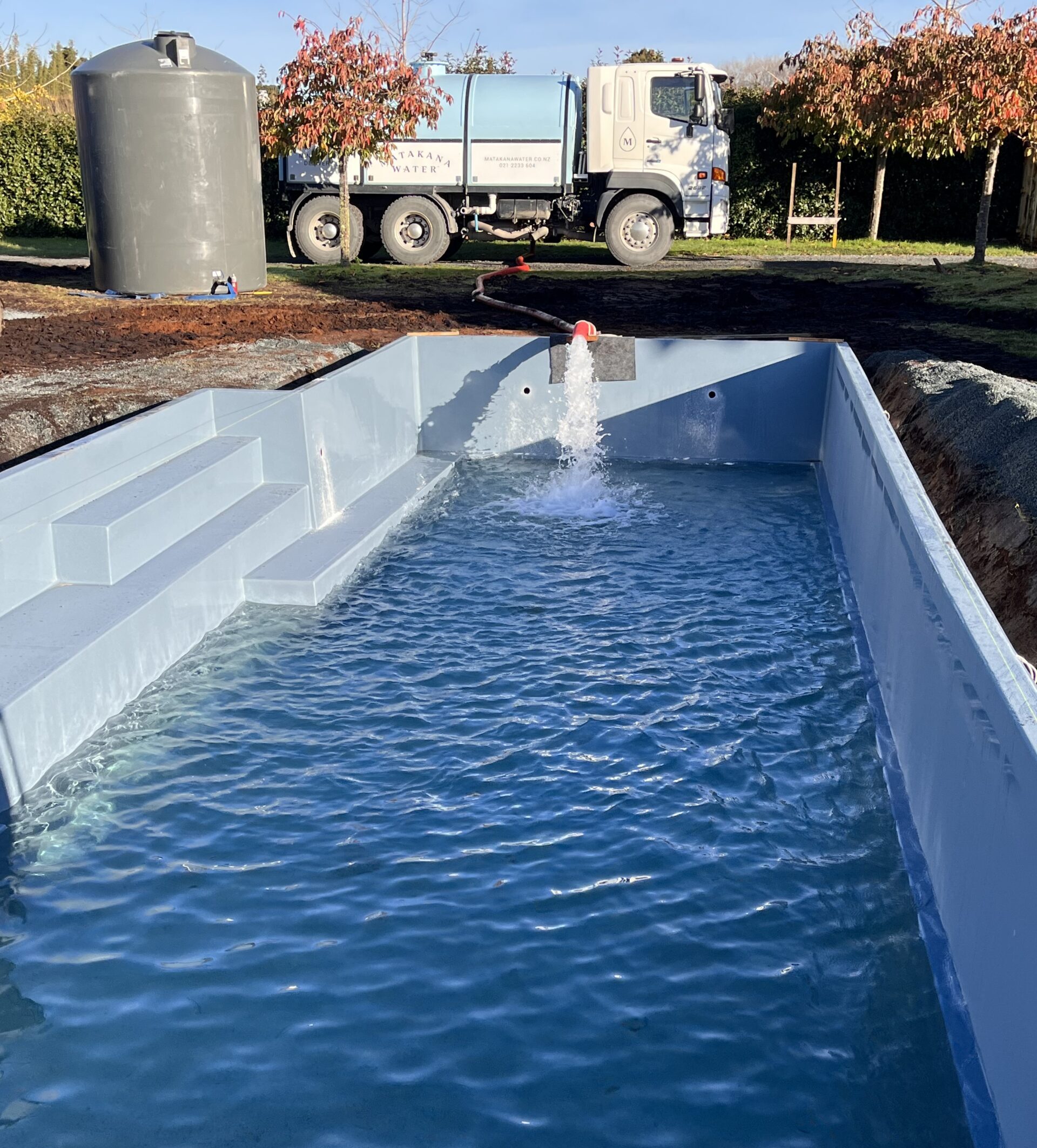 IMG_0894 Matakana Water tanker truck filling a newly installed pool via hose, with a water tank alongside